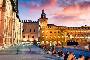 Colorful spring sunset on the main square of City of Bologna with Palazzo d'Accursio and facade of Basilica di San Petronio. Great cityscape of Bologna, Italy, Europe. Traveling concept background.