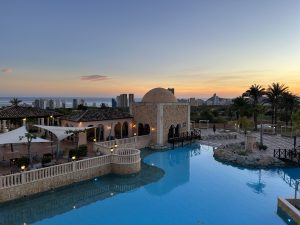 Grosser Pool mit Hotel im Hintergrund und Sonnentuntergang.
