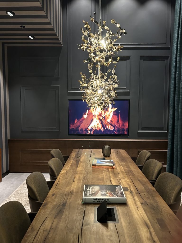 Dark green meeting room with table and chairs and lights.