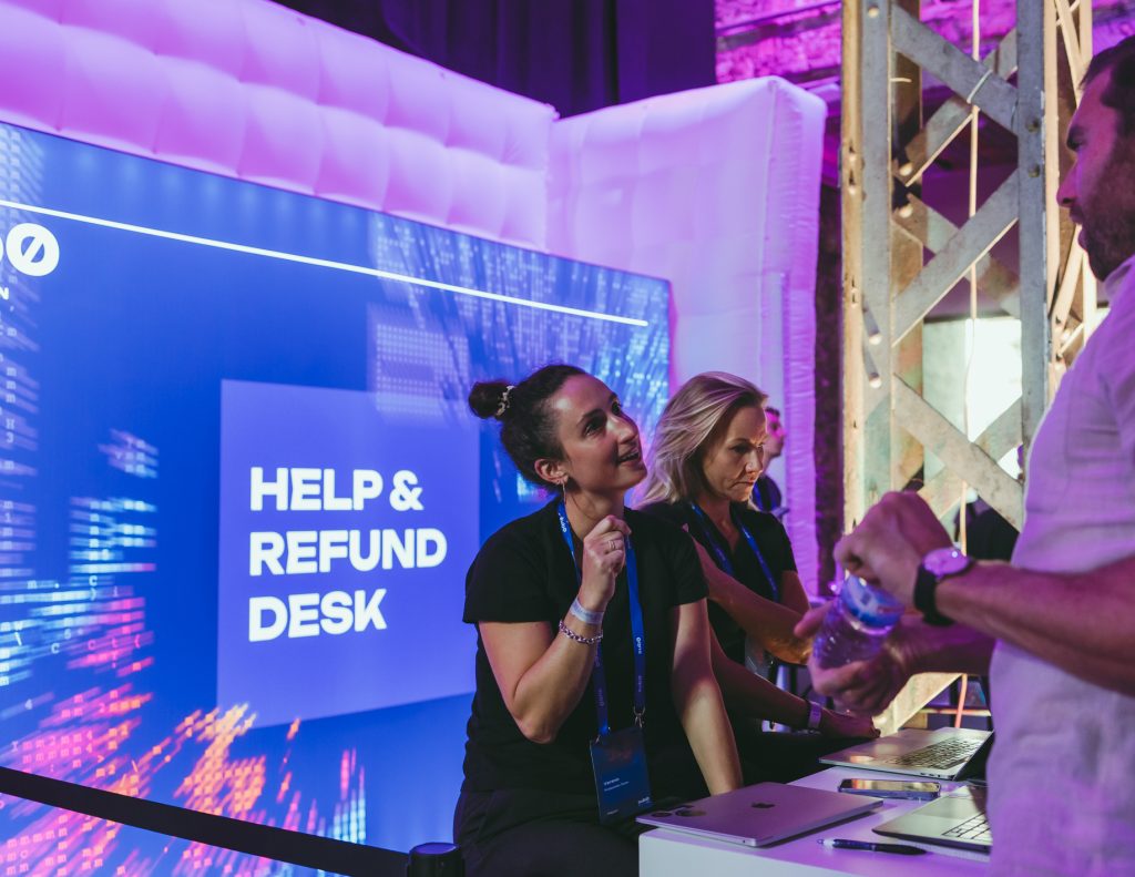 2 Frauen beim Hospitality desk, Unterhaltung mit Teilnehmer.