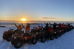 Gruppentour ATV's im Schnee bei Sonnenuntergang.