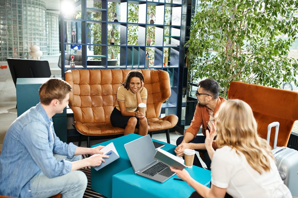 Team in Besprechung sitzend auf Sofas mit Laptops.