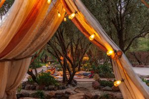 Teepee-Zelt bei Sonnenuntergang in einem grünen Garten – eine stimmungsvolle Kulisse für Outdoor-Events, Retreats und besondere Gruppenmomente.