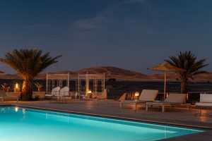 Luxuriöses Wüstenhotel mit Swimmingpool und Sanddünen im Hintergrund – eine exklusive Location für Incentive-Reisen, Team Retreats und besondere Wüstenerlebnisse in Marokko.