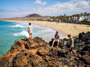 Person am Sandstrand mit Blick auf einen Vulkanberg auf Lanzarote