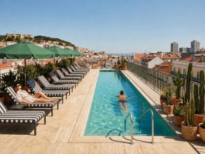 Rooftop-Pool mit Liegestühlen auf einer Hotelterrasse in Lissabon mit Blick über die Stadt