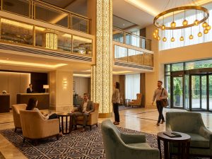 Elegante Hotellobby in Lissabon mit Kronleuchter, offener Galerie und Gästen im Eingangsbereich