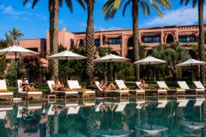KI-generierte Visualisierung eines Luxushotels in der Palmeraie bei Marrakesch mit Pool und Sonnenliegen, geeignet für Firmen-Retreats und Team Offsites