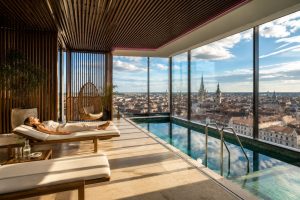 Innenpool mit Panoramafenstern und Blick über die Skyline von München