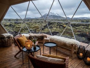 Gemütlicher Lounge-Bereich einer Lodge in Island mit Sitzkissen und Panoramafenster zur Berglandschaft