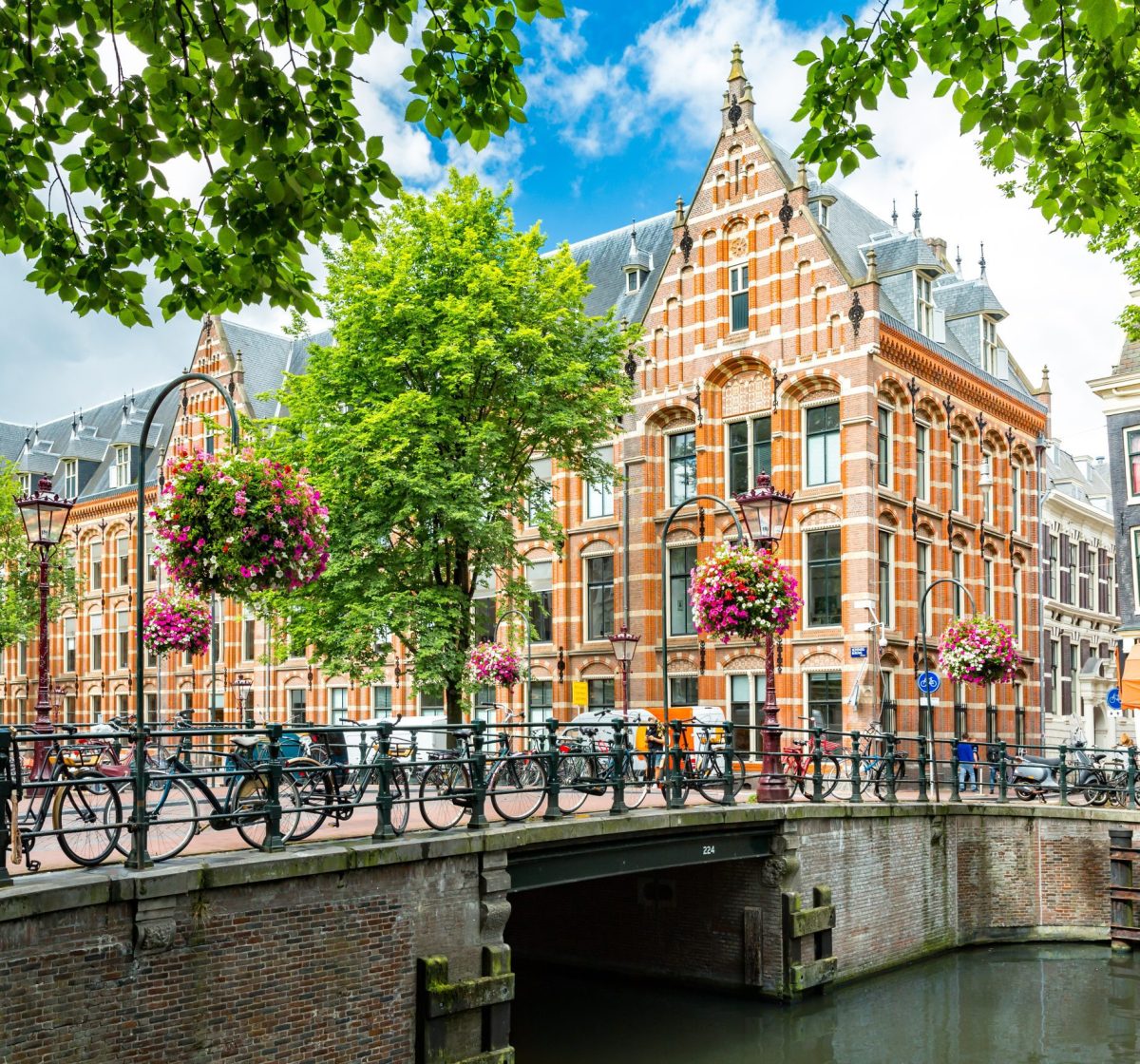 Grachten in Amsterdam mit Fahrrädern auf einer Brücke und einem historischen Gebäude im Hintergrund